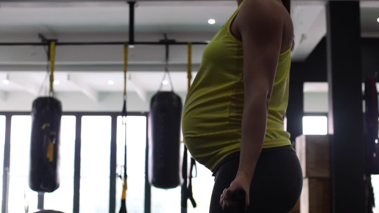 modelo de fitness femenino embarazada haciendo ejercicio de peso corporal en un gimnasio para mantenerse en forma durante su tercer trimestre de embarazo-5