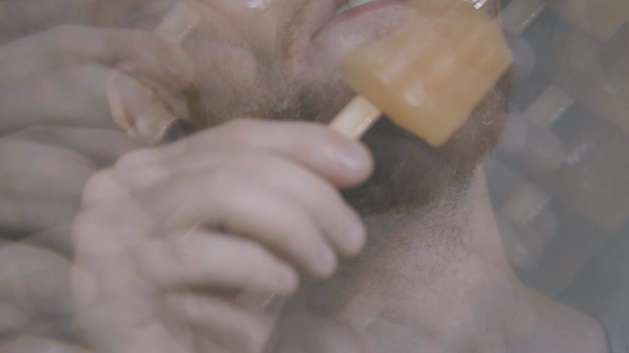 un niño feliz muerde una paleta de naranja, filmada a través de un filtro de caleidoscopio y en cámara lenta