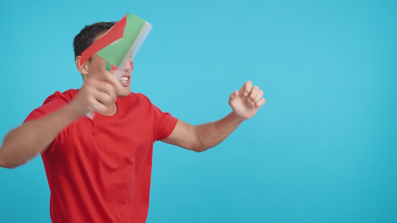 Man cheering for Portugal waving a national flag looking away