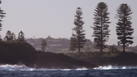 Waves-break-onto-the-rocky-shoreline-of-a-small-coastal-town