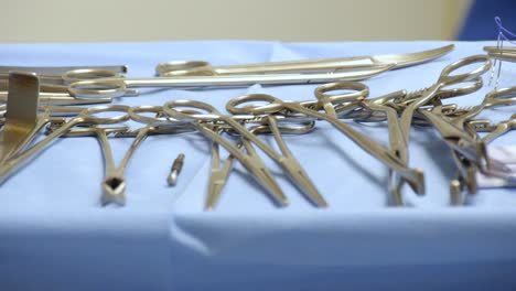 close-up of a sterile surgical tray full of operating instruments with motion of doctors passing in the background