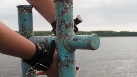 woman's hands with bracelets on them. woman cuffs herself to old rusty bollard on wooden pier to express protest.