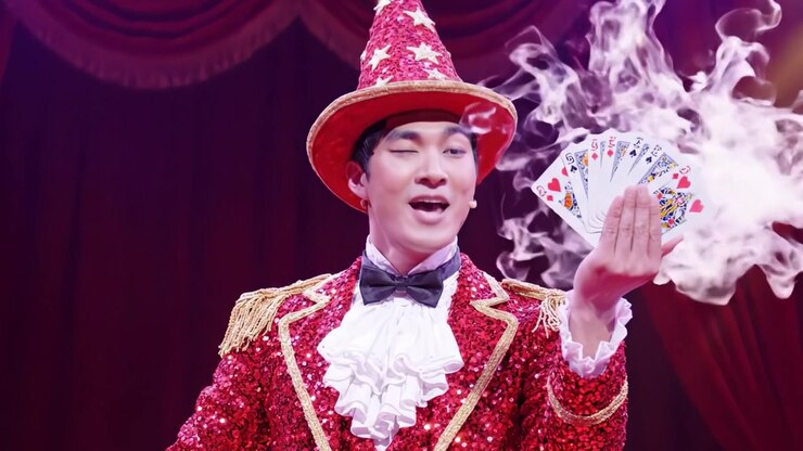 Un mago abbagliante in un abito rosso scintillante incanta il pubblico con uno spettacolo di magia, caratterizzato da incredibili trucchi di carte ed esibizioni entusiaste.