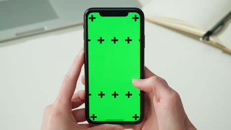 manos sosteniendo un teléfono inteligente con una pantalla verde