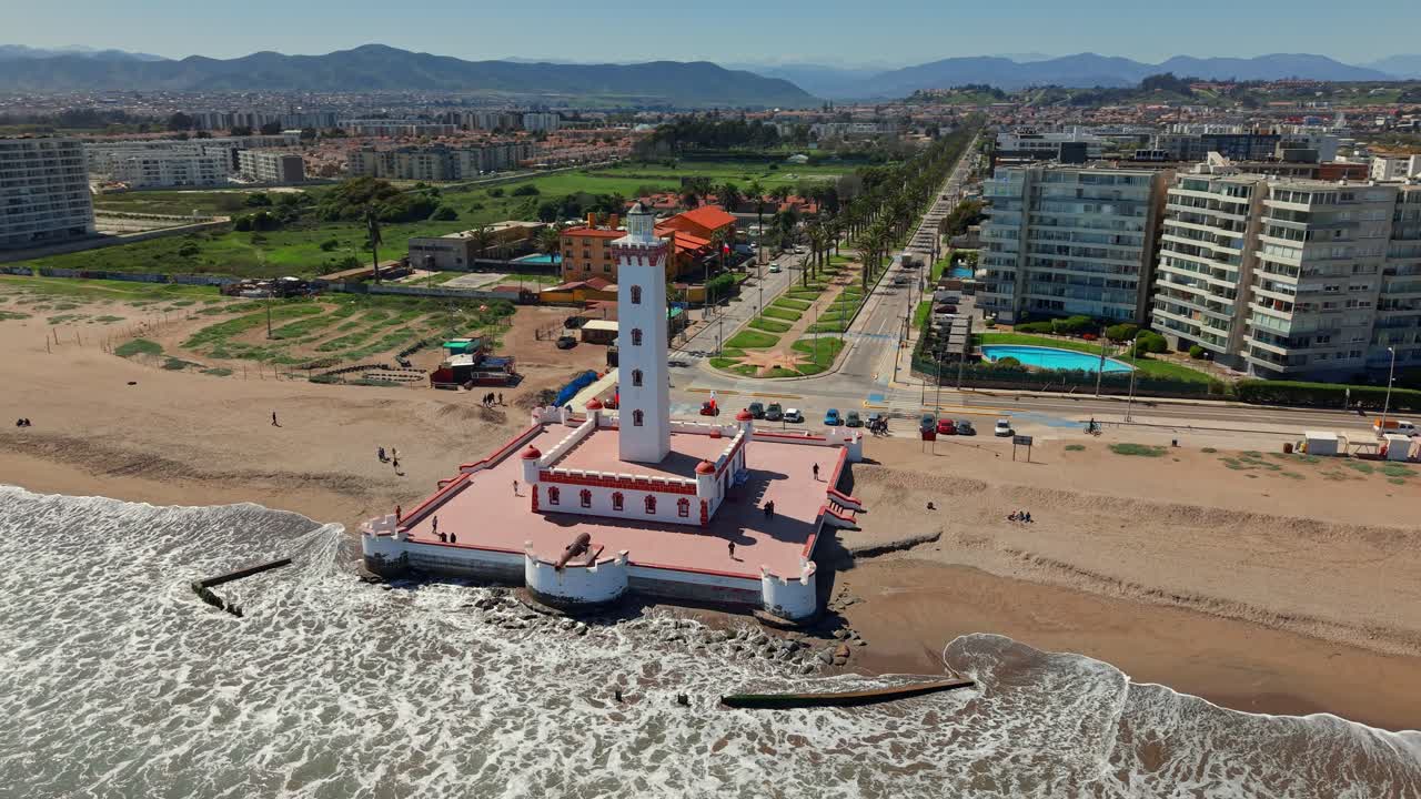 Fly over the Monumental Lighthouse of La Serena on a sunny day with the palm tree promenade in the background