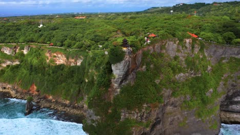 uluwatu temple on cliffs above tropical sea in bali, indonesia - aerial drone shot