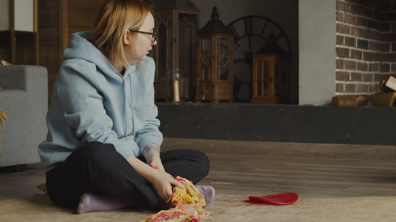 그녀의 불독이 그녀 주위를 걷는 동안 집 거실 바닥에 앉아있는 빨간 머리 여자