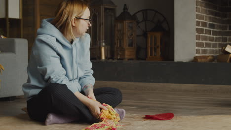 red haired woman sitting on the floor in the living room at home, while her bulldog walks around her