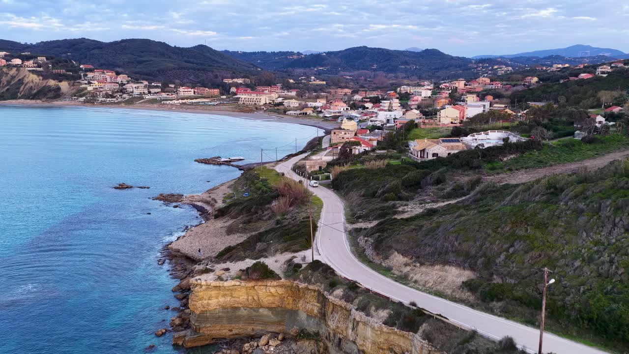 Filmato aereo panoramico della costa e della baia di Agios Stefanos a Corfù, in Grecia, con lussureggianti colline verdi e acque turchesi del Mar Ionio al sole del tardo pomeriggio