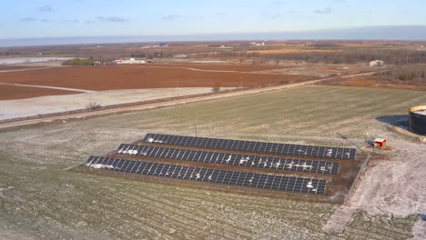 Aerial-drone-view-of-a-lightly-snow-covered-solar-panel-station-powering-a-farm