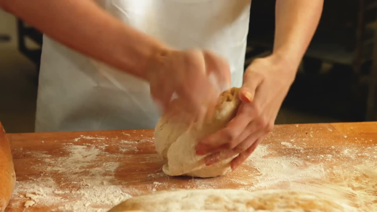 Panettiere femminile che impasta una pasta