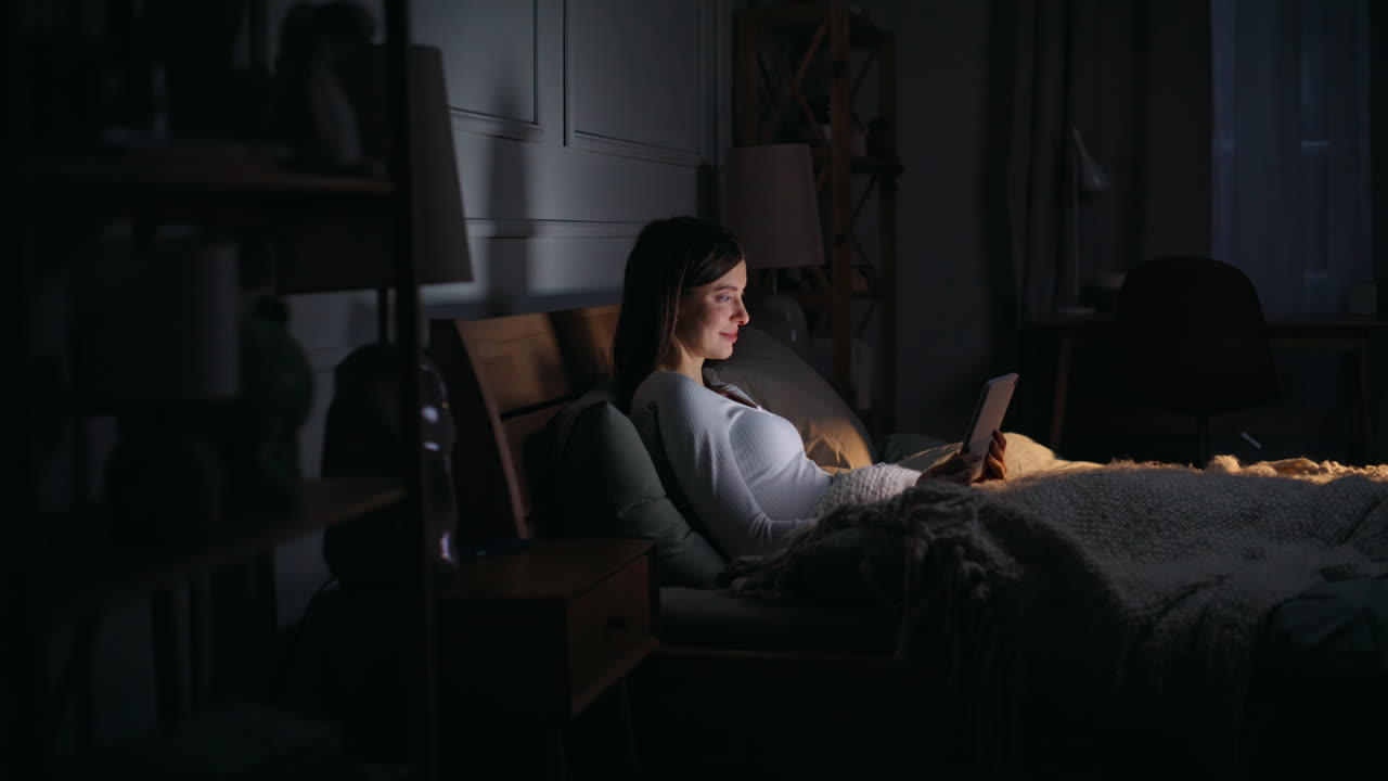 Lady surfing internet bedtime lying cozy dark bedroom. Freelancer reading email