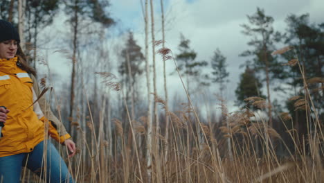 hiker stops and looks around while surrounded by tall grass at the edge of the forest