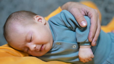 lovely newborn kid sleeping and making faces in his sleep. beautiful little toddler resting in father's arms. close up.