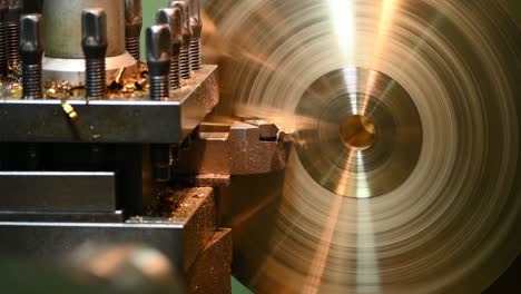 escena de primer plano la máquina de torno áspera cortando las piezas del disco de bronce con herramientas de torno.