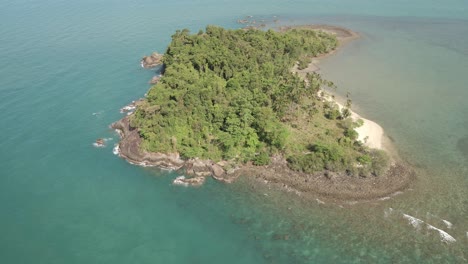 Aerial-ascending-shot-looking-down-on-tropical-island-beach,-jungle-and-rocky-coastline