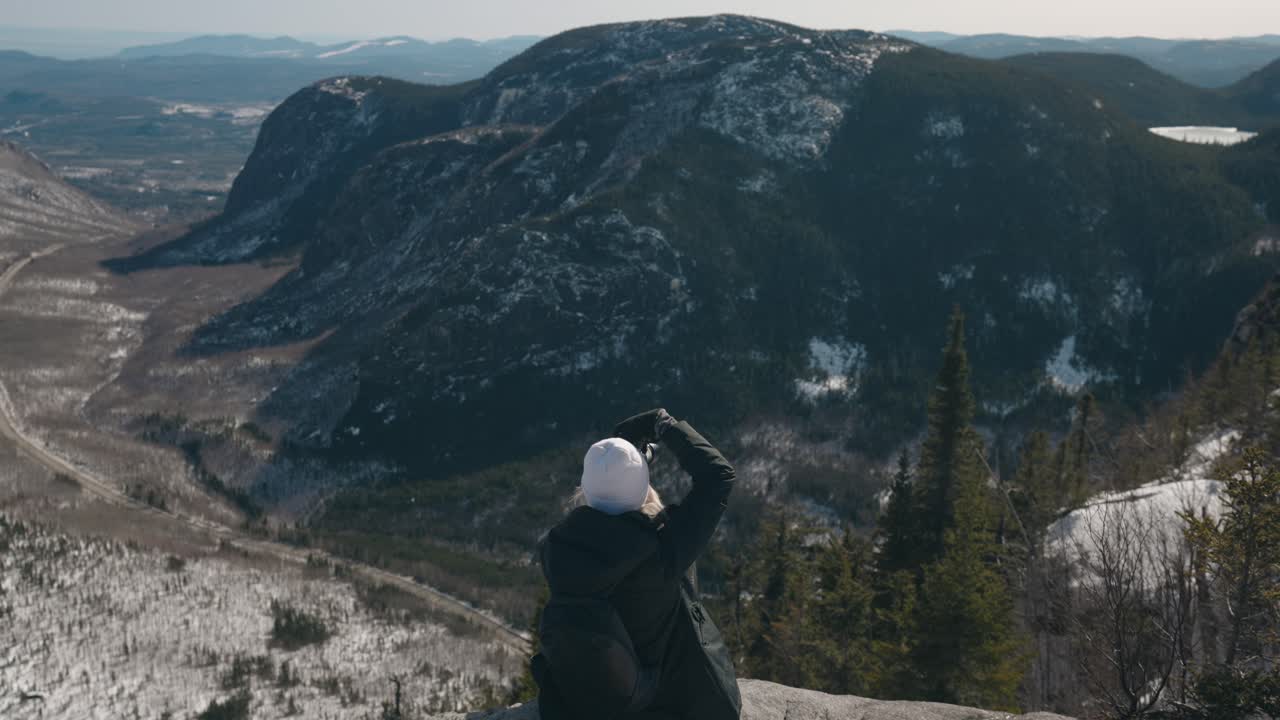 niña sentada en el borde de la montaña tomando fotos en el monte de la cúpula en quebec, canadá