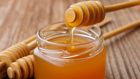 golden honey in a glass jar with wooden dipper