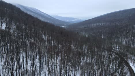 flying over a snowy, beautiful mountain valley with a remote road below