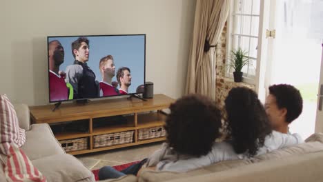 Composite-of-happy-family-sitting-at-home-together-watching-sports-event-on-tv