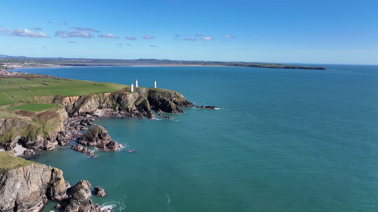 Drone flyver langsomt langs Metalman-tårnene ved indgangen til Tramore Bugt, Waterford, Irland, med Brownstown Head i baggrunden. Disse navigationspiller tjente skibsfarten i gamle dage. Det er en lys forårsmorgen.