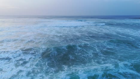 Moody-ocean-textures-created-by-crashing-waves,-drone-orbit-shot