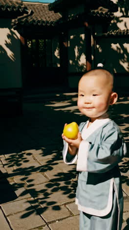 baby in traditional chinese clothing with an apple