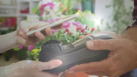 animation of light circles floating over caucasian woman paying with a smartphone