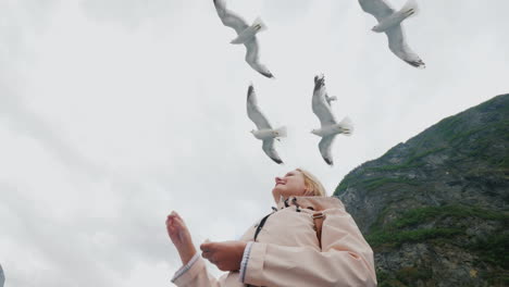 a woman is feeding a gull that flies by trust and tame the concept journey through the fjords of nor