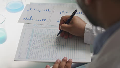 hands of laboratory technician recording experiment results in report