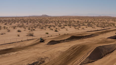 vista de perfil aéreo volando por motociclista de motocross en la pista del desierto