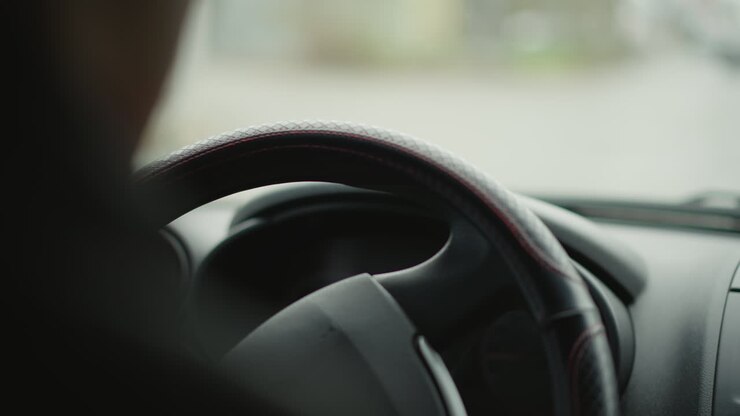 Green turn signal indicator blinking and clicking on dashboard as driver navigates busy urban intersection, close focus on illuminated lights and blurred city vehicles passing outside windshield