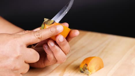 hands skillfully peel a ripe persimmon fruit