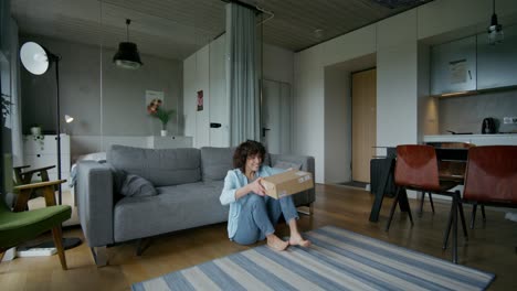 woman excitedly unboxing a package in a modern apartment