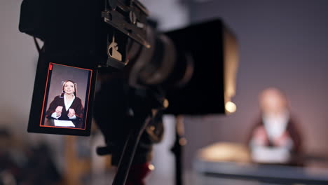 modern professional camera on tripod filming a lady speaking. close up. footage in studio. blurred backdrop.