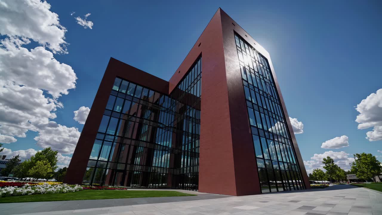 Dynamic low-angle shot of a modern glass building under a vibrant sky, capturing sunlight