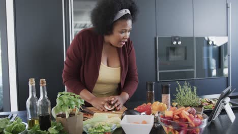 african american plus size woman cooking in kitchen and using tablet, unaltered, slow motion