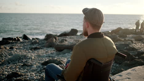 disabled man contemplates the ocean at sunset