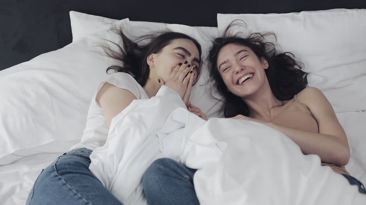 Two happy women laughing together in bed