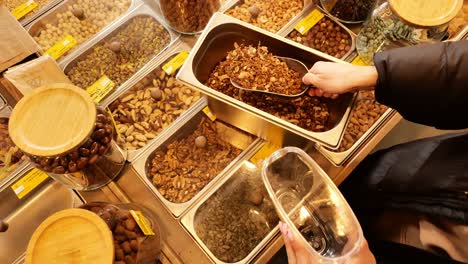 Person scoops musli into reusable jar showing plastic-free zero waste shopping
