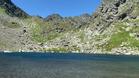 lago en el medio de grandes montañas con excursionistas, panorámica en mano