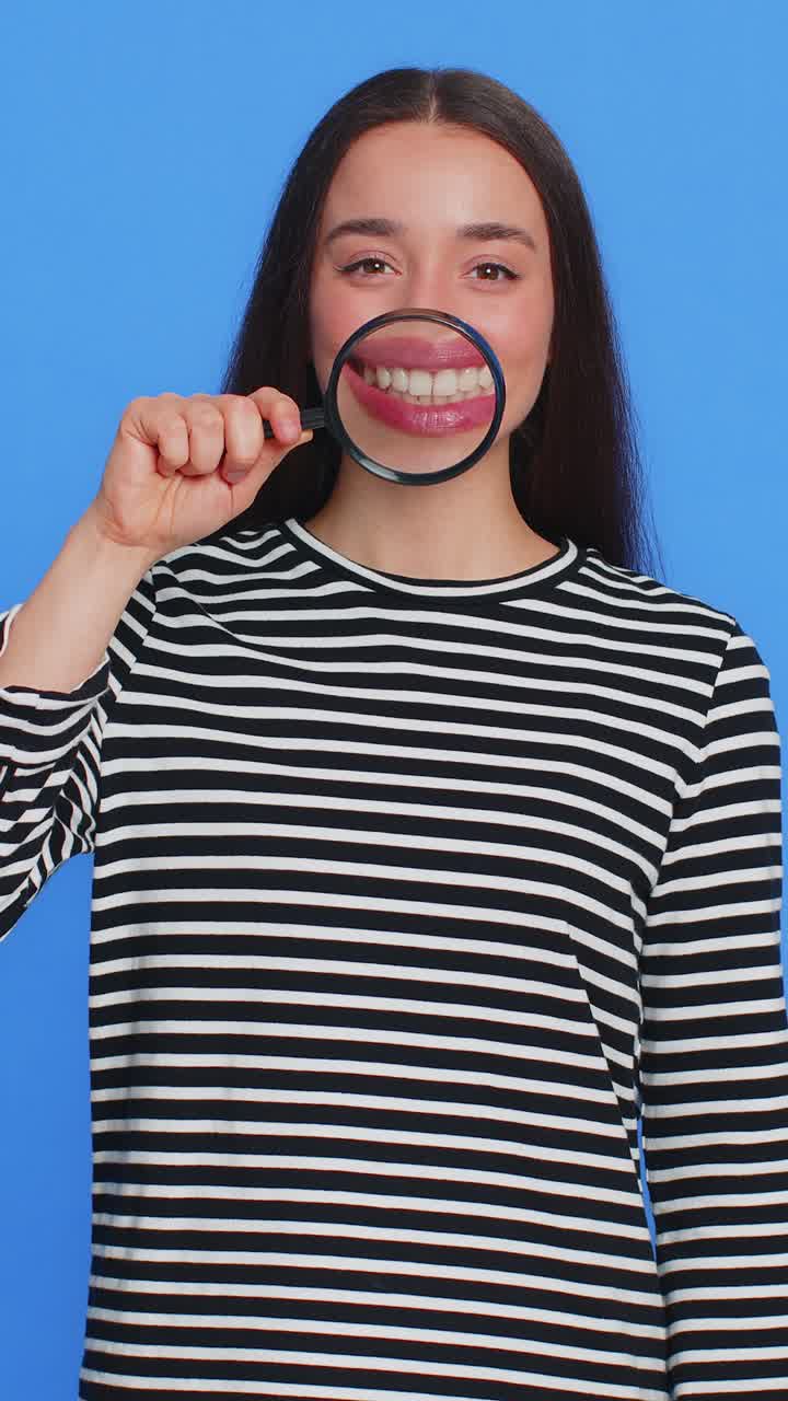 feliz mujer joven sonriente sosteniendo una lupa en los dientes cuidado de la salud higiene concepto de estomatología