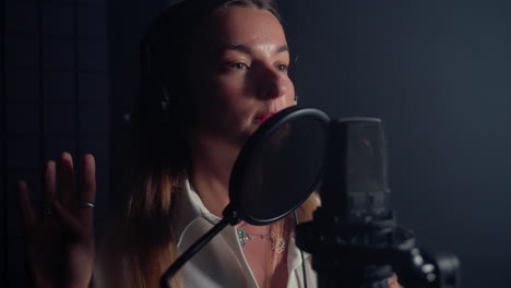 mujer cantando en el micrófono en el estudio de grabación