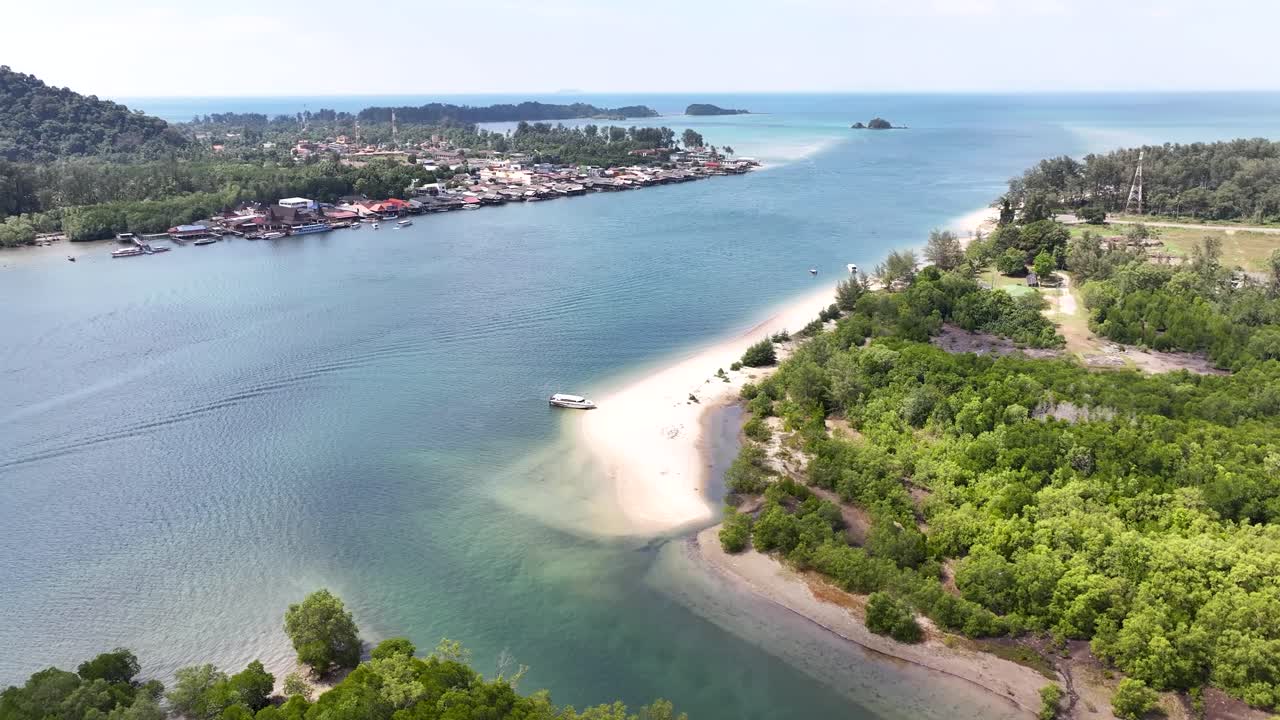 Inlet with boat and landscape of Koh Lanta Island with village and tropical surroundings.