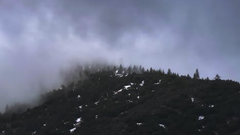 dramatic cloud coverage moving swiftly over the snow-covered pine forest mountains of frazier park southern california aerial telephoto 60fps