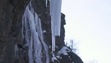salpicaduras congeladas, témpanos de hielo blancos y afilados de carámbanos en la superficie de la roca cerca de la cascada de la montaña