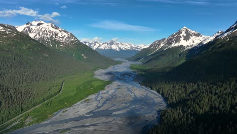 River-Flowing-Through-Snowy-Mountains-And-Vegetation-In-Alaska,-USA