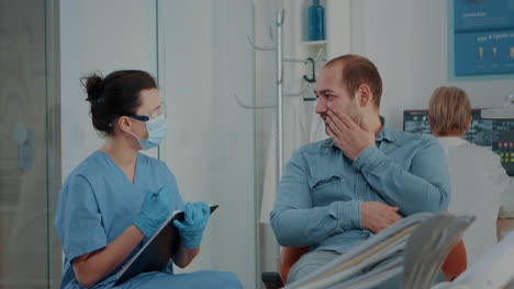 paciente explicando el dolor de dientes a la enfermera odontológica en una visita estomatológica