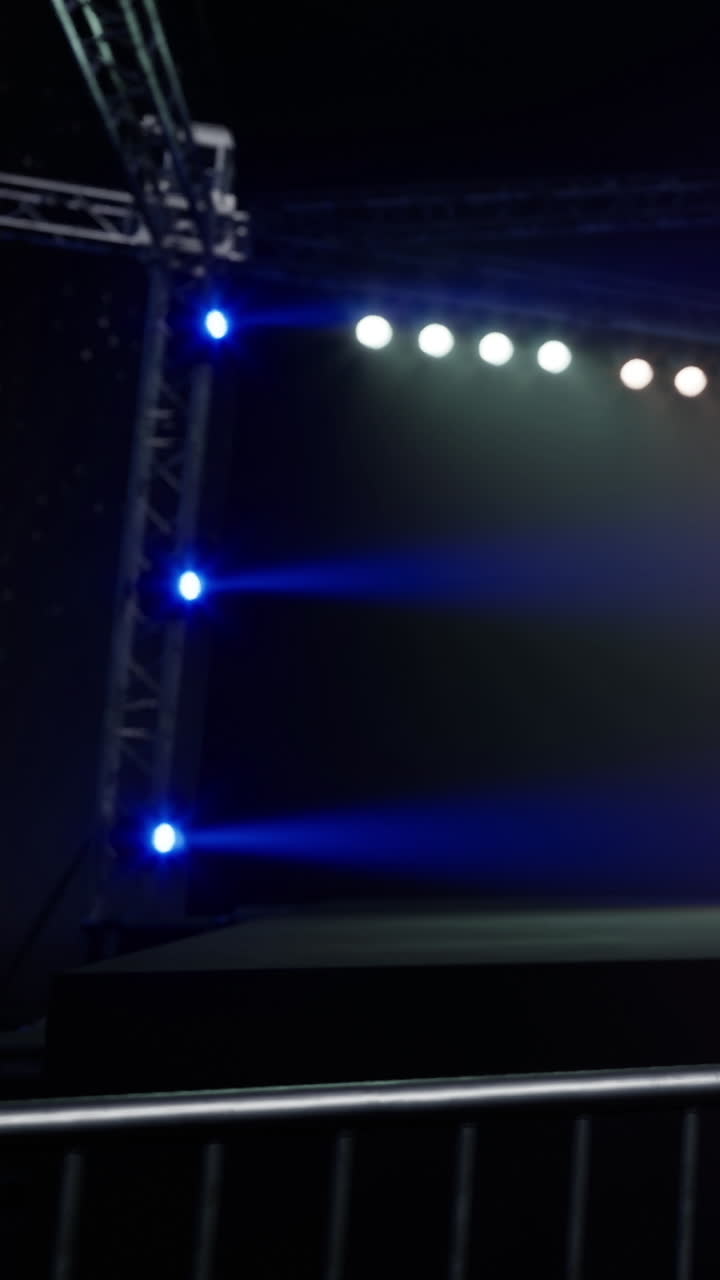 Stage lights shine in a dark venue during a live performance setup