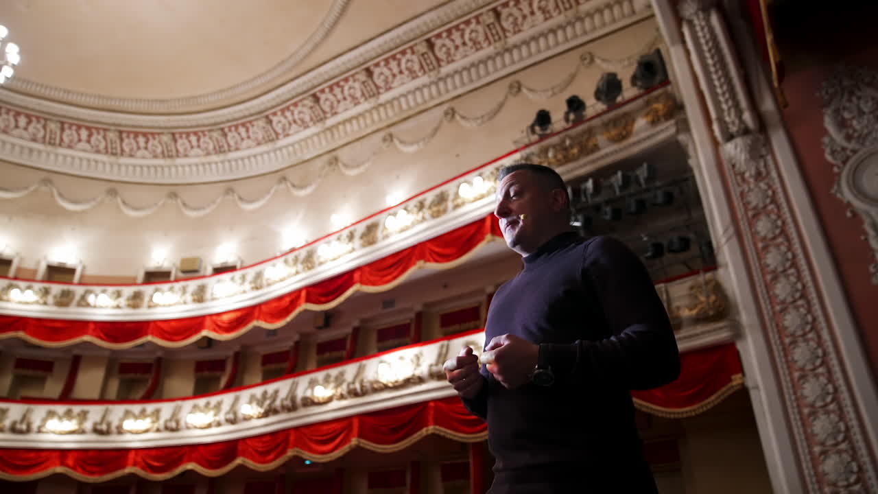 Actor man on a stage. Man wearing sweater performing on a scene in theatre. View from below.